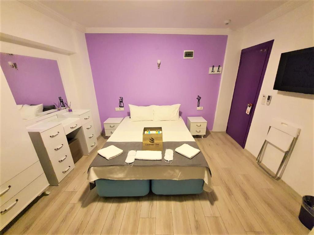 um quarto com paredes roxas e uma cama num quarto em Lavender Otel em Cesme