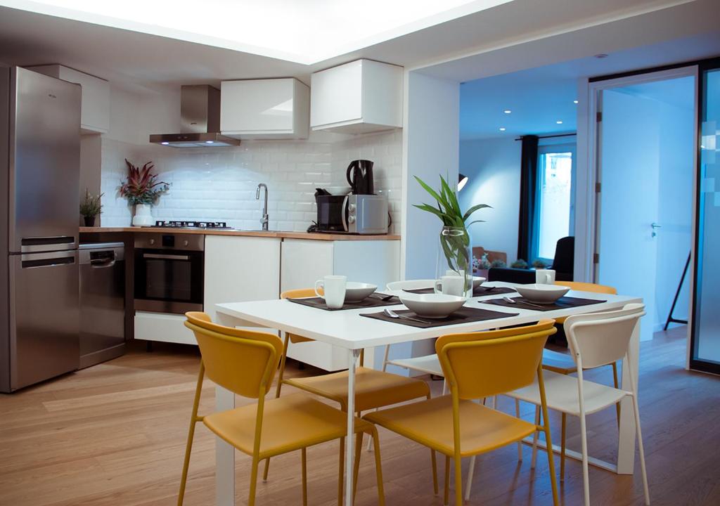 a kitchen with a white table and yellow chairs at Smartflats - Central Brussels in Brussels