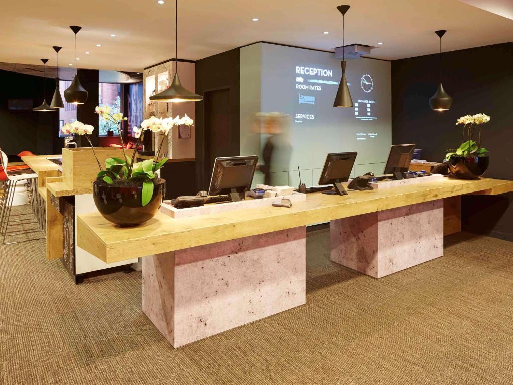 a lobby with a reception desk with laptops on it at ibis Reading Centre in Reading