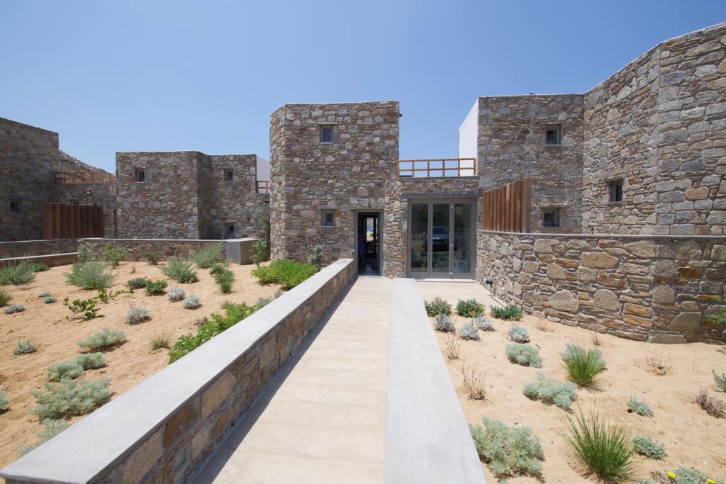an exterior view of a stone building with a walkway at Ammoa Beach Residences in Vayiá