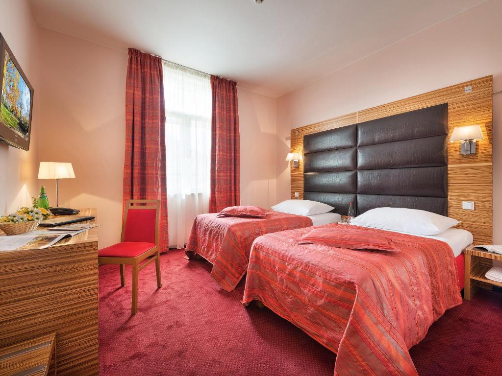 プラハにあるEA ホテル ソナタのベッド2台とテレビが備わるホテルルームです。