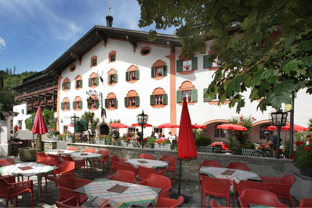 a restaurant with tables and red umbrellas in front of a building at Hotel Lukashansl in Bruck an der Großglocknerstraße