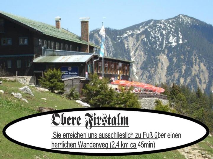 un panneau devant un bâtiment sur une montagne dans l'établissement Berggasthof Obere Firstalm, à Schliersee