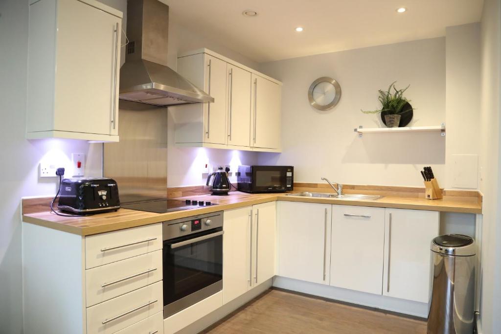 eine Küche mit weißen Schränken und einem Herd mit Backofen in der Unterkunft Letting Serviced Apartments - Central St Albans in St Albans