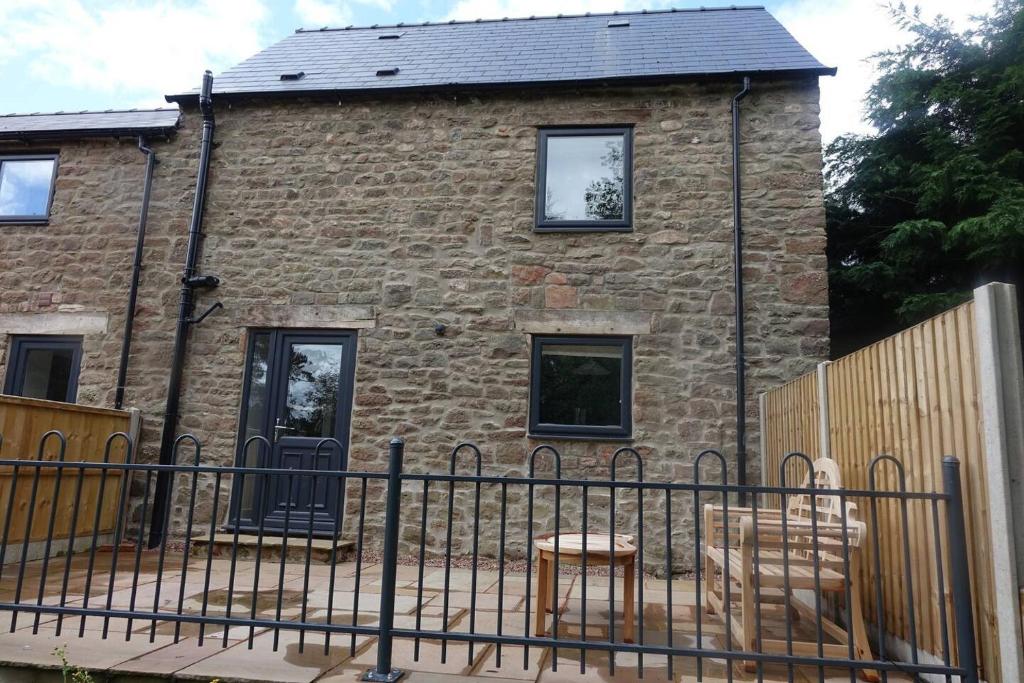 uma casa de tijolos com uma cerca em frente em Wren is a stunning 1-Bed Cottage near Coleford em Coleford