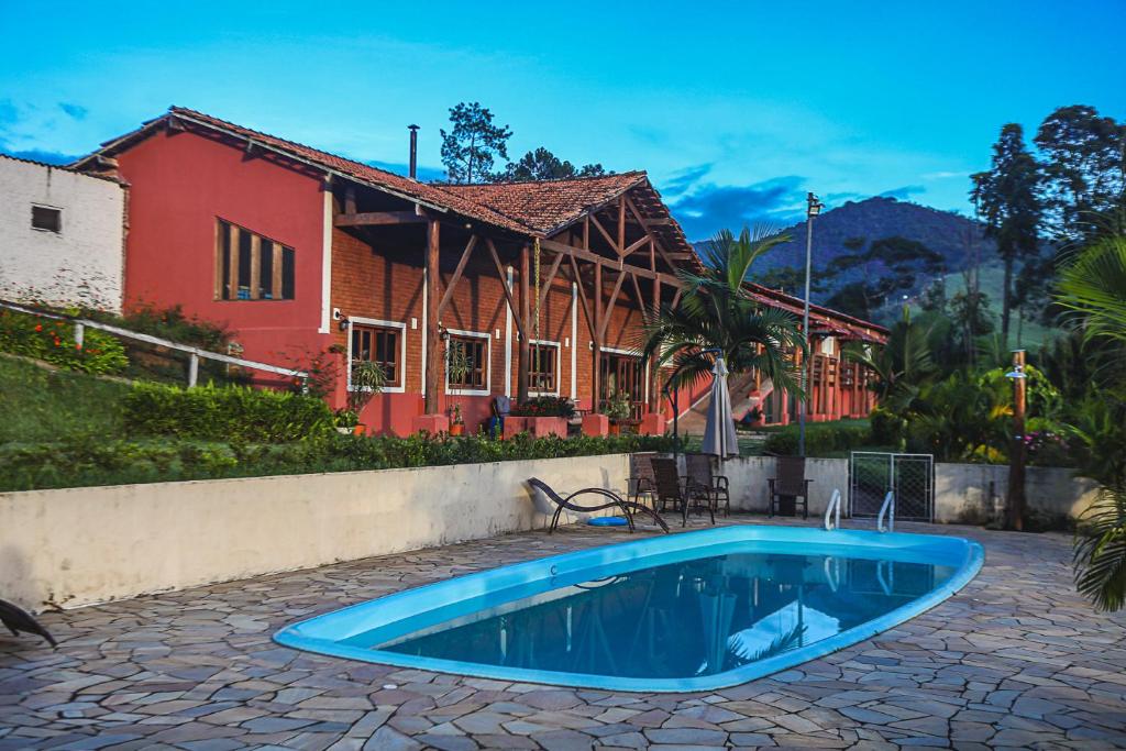 a house with a blue pool in front of a house at Pousada Pedra da Mina in Passa Quatro