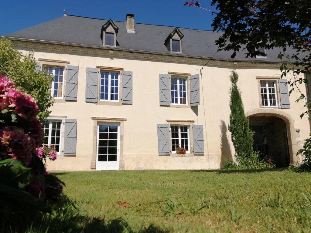 Castetnau-Camblong的住宿－Domaine de la Castagnère，大型白色房屋,设有灰色百叶窗