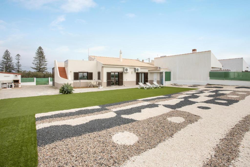 a house with a gravel driveway in front of a yard at Vivenda Idalina in Sagres
