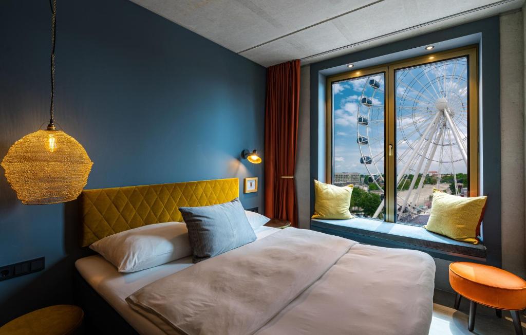 ein Schlafzimmer mit einem Bett und einem Fenster mit einem Riesenrad in der Unterkunft gambino hotel WERKSVIERTEL in München