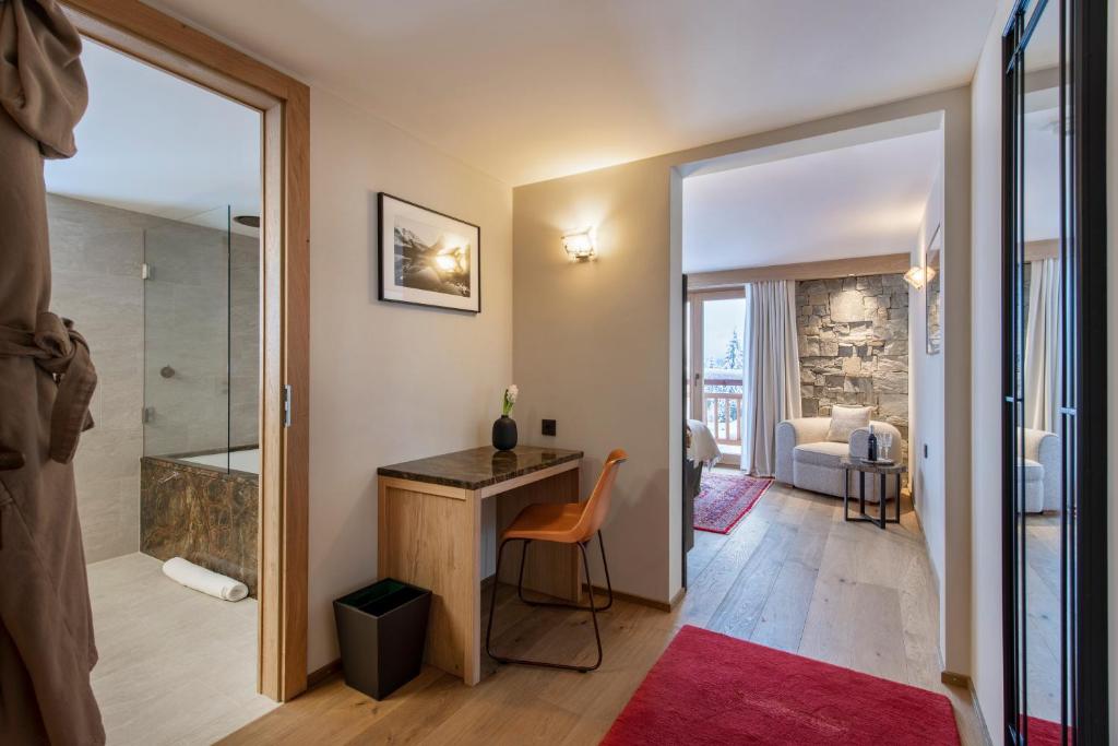 a bathroom with a walk in shower and a desk in a room at Hôtel de Verbier SUP in Verbier