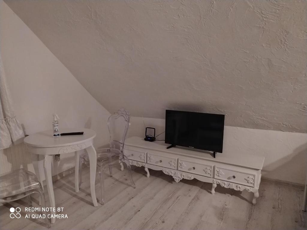 ein Wohnzimmer mit einem TV auf einer Kommode mit einem Tisch in der Unterkunft White Apartment in Elblag