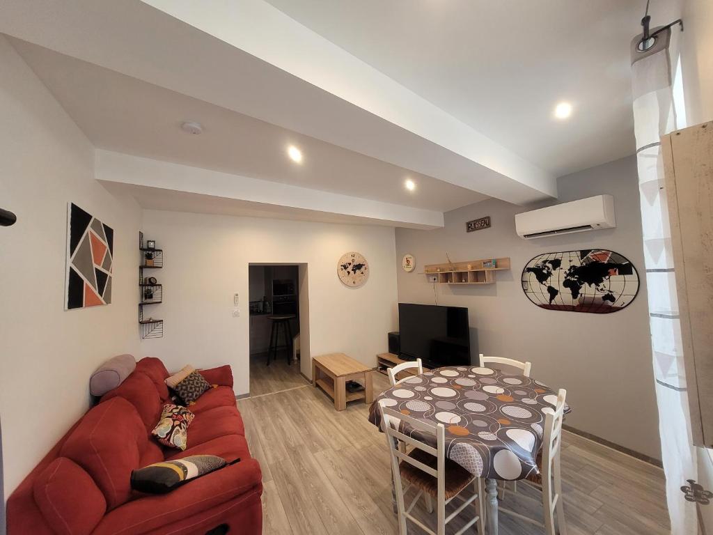 a living room with a red couch and a table at Gîte du ruisseau in Nissan-lez-Enserune