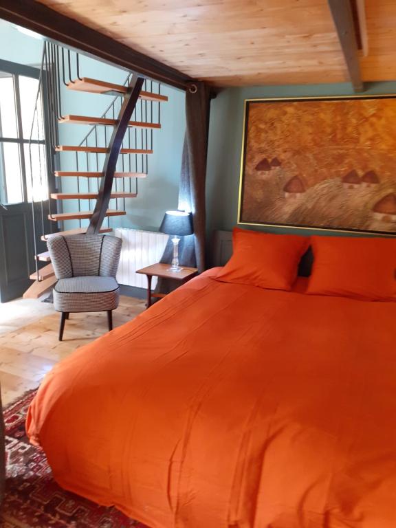 um quarto com uma cama laranja e uma cadeira em studio familial LE PETIT SULLY em Sully