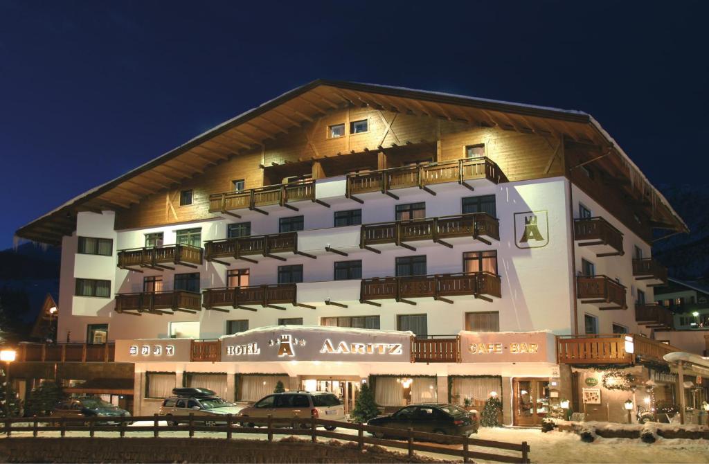 a large building with cars parked in front of it at Hotel Aaritz in Selva di Val Gardena