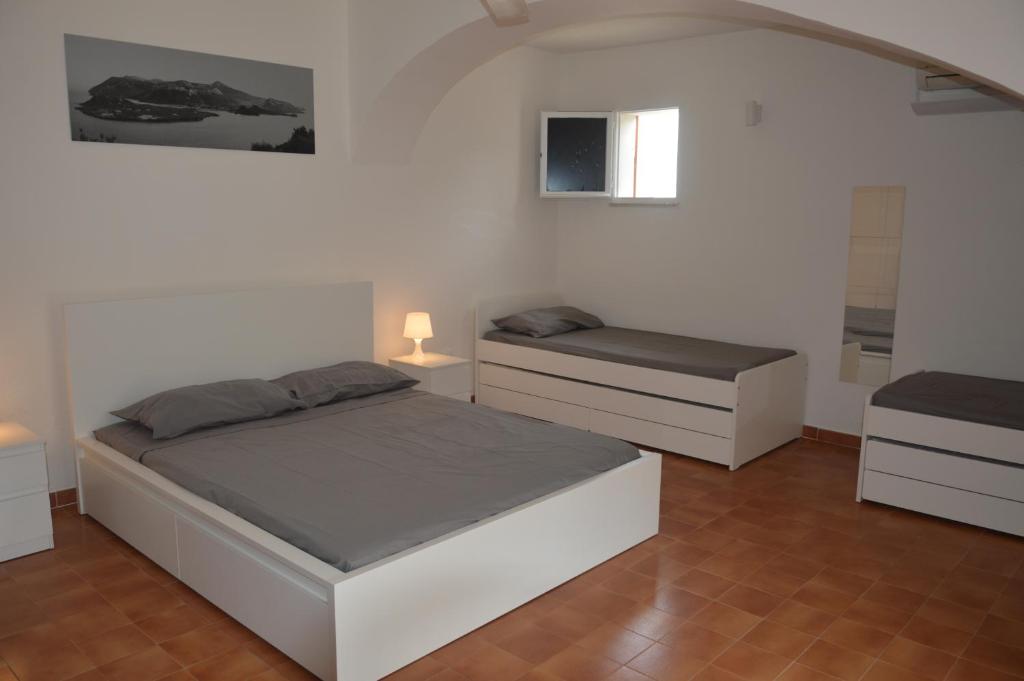 a white bedroom with two beds and a window at Casa Luvi in Vulcano