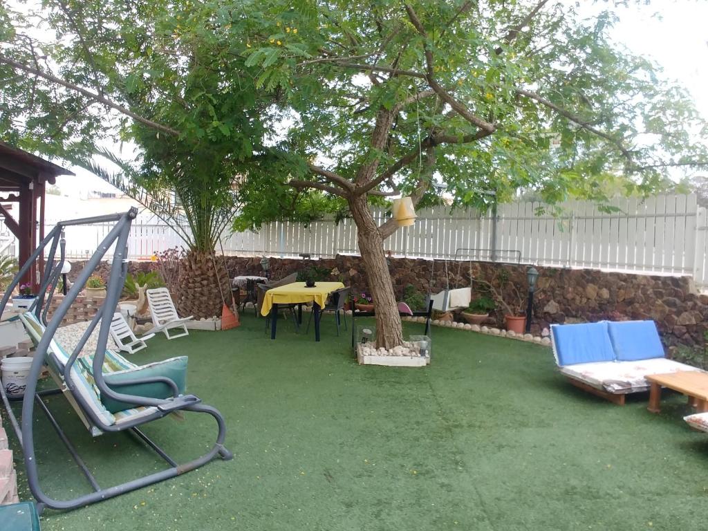 a yard with a tree and chairs and a swing at Carmela Studio in Arad