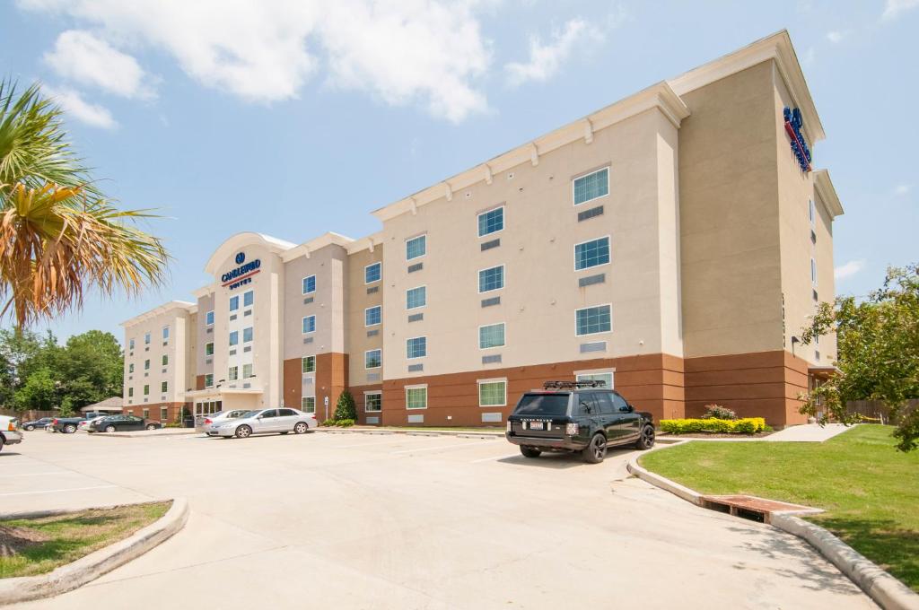 a large building with a car parked in a parking lot at Candlewood Suites - Baton Rouge - College Drive by IHG in Baton Rouge