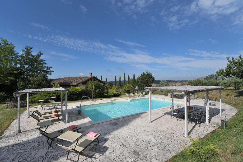 una piscina con sillas y sombrillas junto a una casa en Il Fornacino, en Rapolano Terme