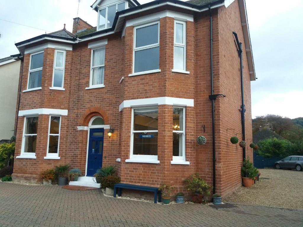 una casa de ladrillo rojo con puerta azul en The Groveside Guest House, en Sidmouth