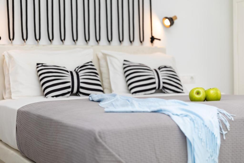 a white bed with black and white pillows and apples at Depis Place and Apartments in Naxos Chora