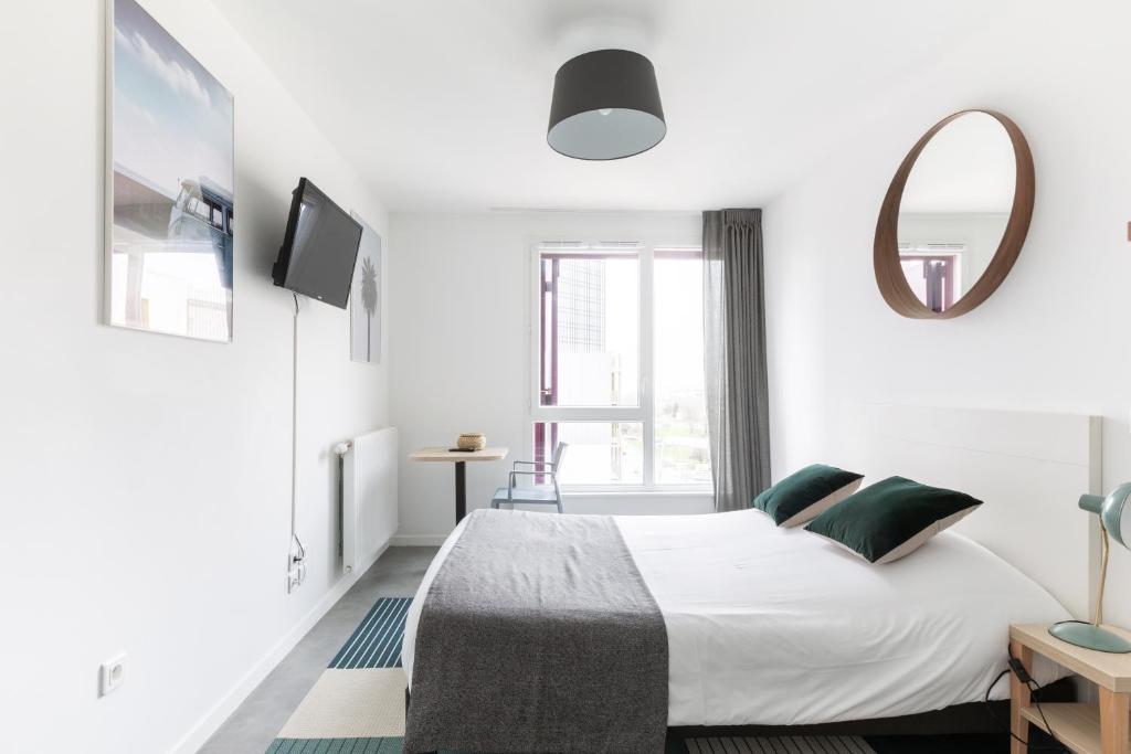 a white bedroom with a bed and a mirror at Student Factory Paris Bagnolet in Bagnolet