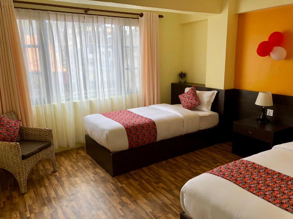 a hotel room with two beds and a chair and a window at Yeti Inn Pvt. Ltd. in Kathmandu