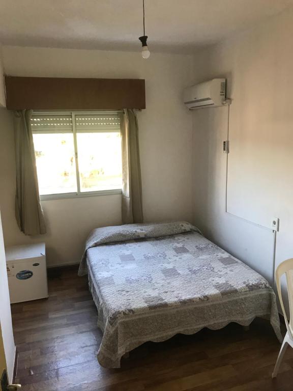 a small bedroom with a bed and two windows at Departamentos LT3 in Las Toscas