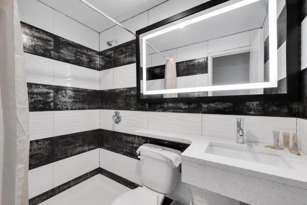 a black and white bathroom with a toilet and a sink at Hotel Mint JFK Airport in Queens