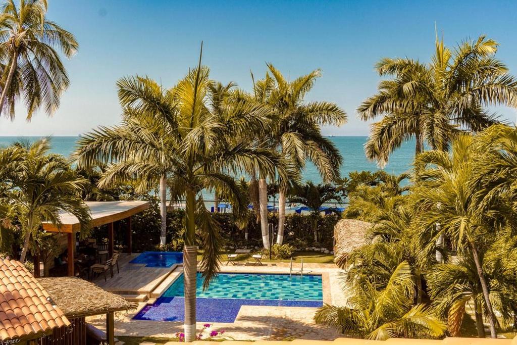 un complejo con piscina, palmeras y océano en Casa Verano Beach Hotel - Adults Only, en Santa Marta