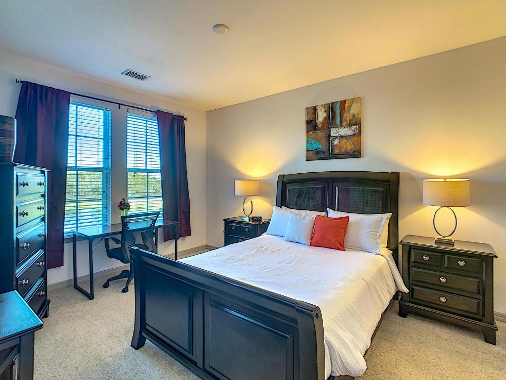 a bedroom with a bed and a desk and windows at Perfect And Close To Disney! in Kissimmee