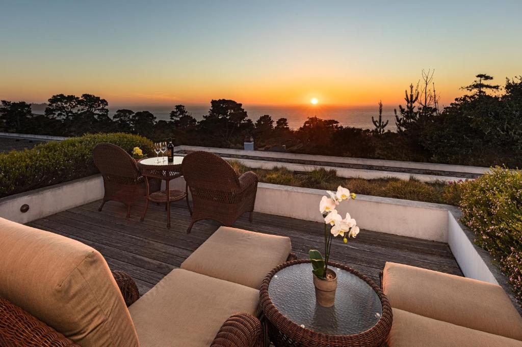 eine Terrasse mit einem Tisch und Stühlen sowie einem Sonnenuntergang in der Unterkunft Tally Ho Inn in Carmel