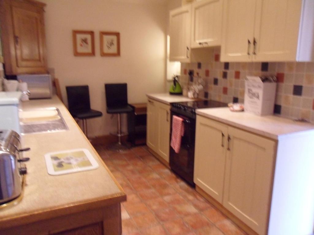 a kitchen with white cabinets and a black appliances at 2 Bed Barn near Newport Shropshire in Newport
