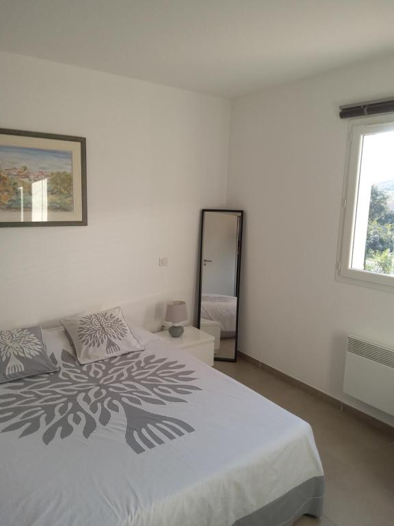 a white bedroom with a bed and a window at Lecci St Cyprien Don Andria in Porto-Vecchio