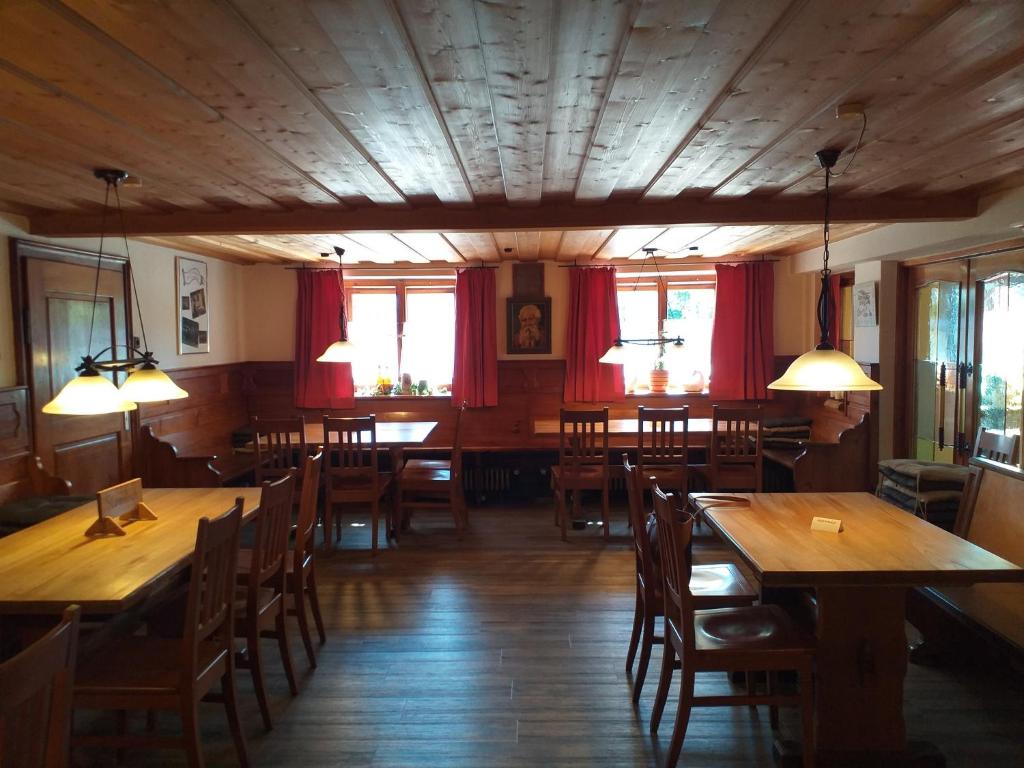 um restaurante com mesas e cadeiras de madeira e cortinas vermelhas em Mesnerwirt em Neukirchen am Teisenberg