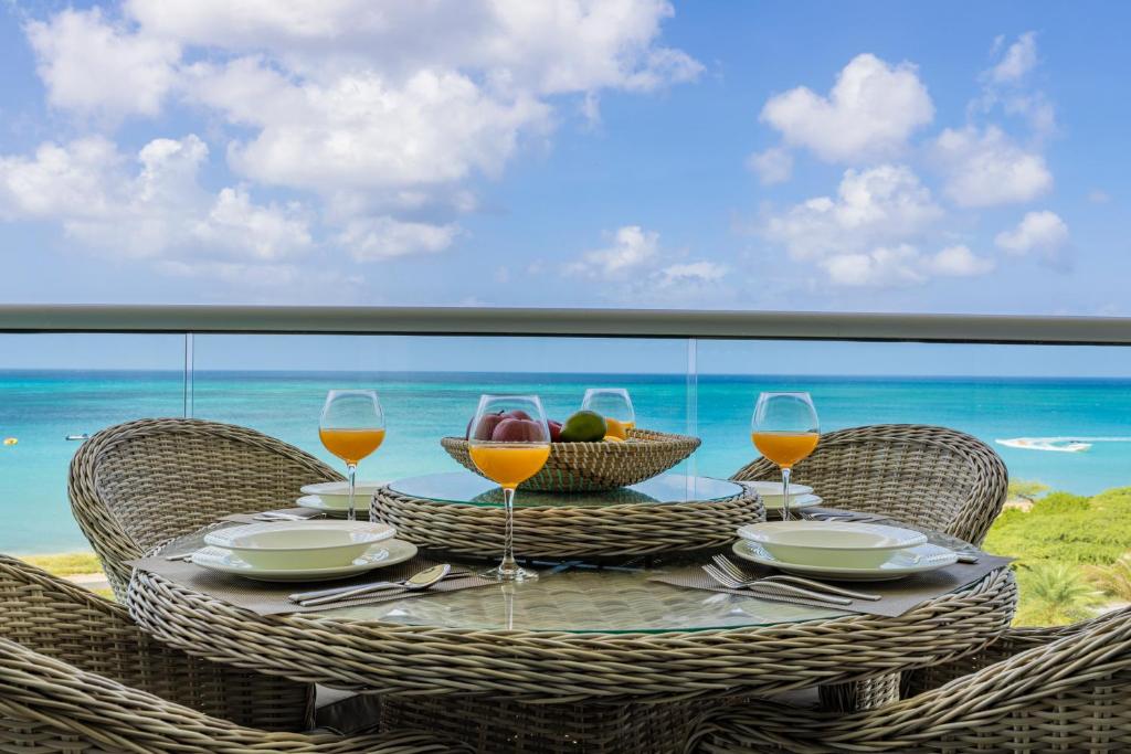 a table with a bowl of fruit and wine glasses at Azure Beach Residences in Palm-Eagle Beach