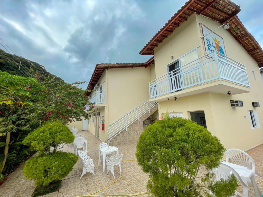 une terrasse avec des chaises et des tables blanches en face d'une maison dans l'établissement Pousada Vila Real Juquehy, à Juqueí