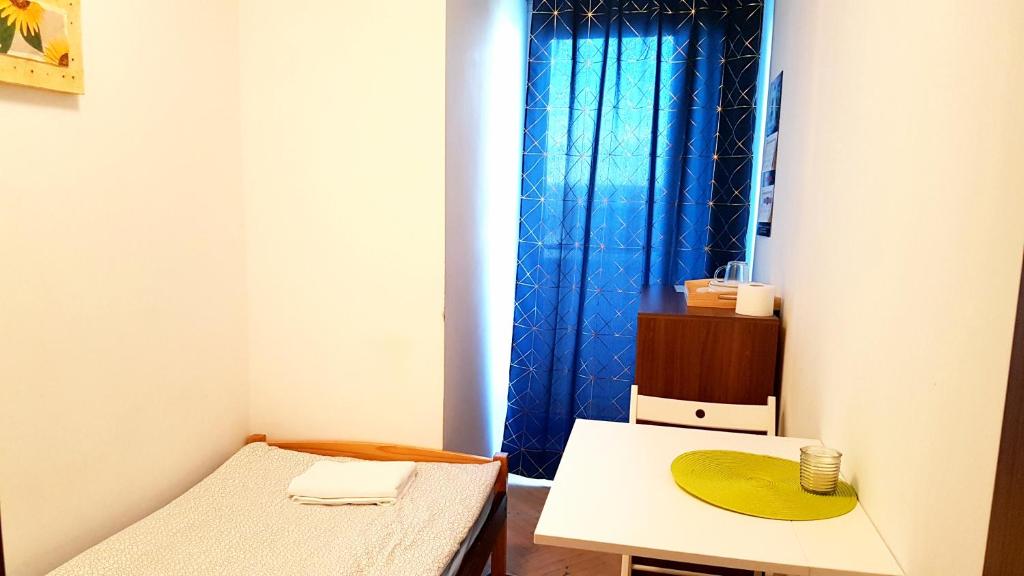 Habitación pequeña con cama y mesa en Niebieski Meander Pokoje blisko metra en Varsovia