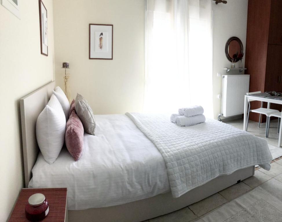 a bedroom with a white bed with pillows and a table at Stergios_Apartments 05 in Kozani
