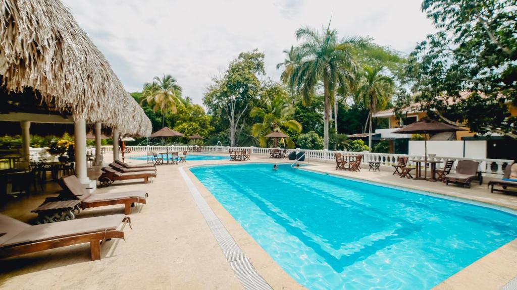 una piscina en un complejo con sillas y sombrillas en Hotel La Iguana de Santa fe De Antioquia, en Santa Fe de Antioquia