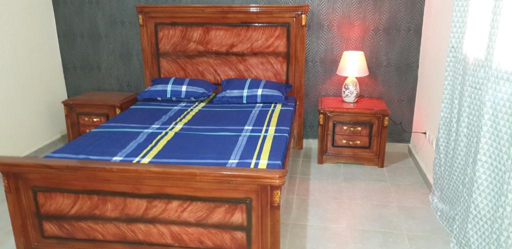 1 dormitorio con 1 cama con sábanas azules y lámpara en Appartement meublé à MBAO en Mbaw Gou Ndaw