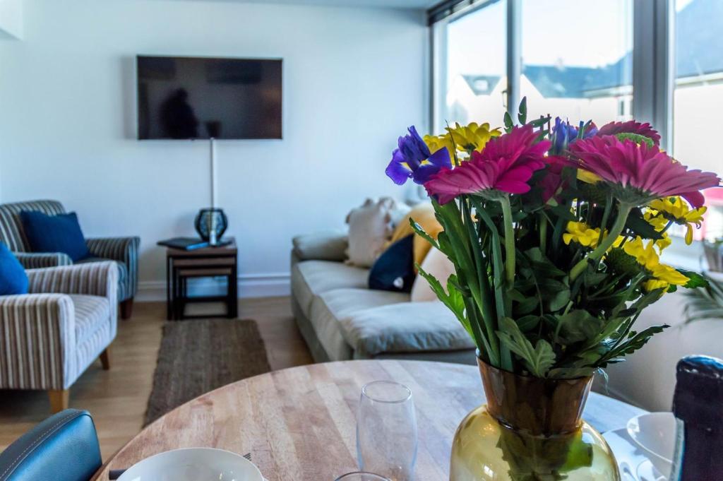 a vase of flowers on a table in a living room at Coppet Cove - 2 Bedroom Apartment - Saundersfoot in Saundersfoot