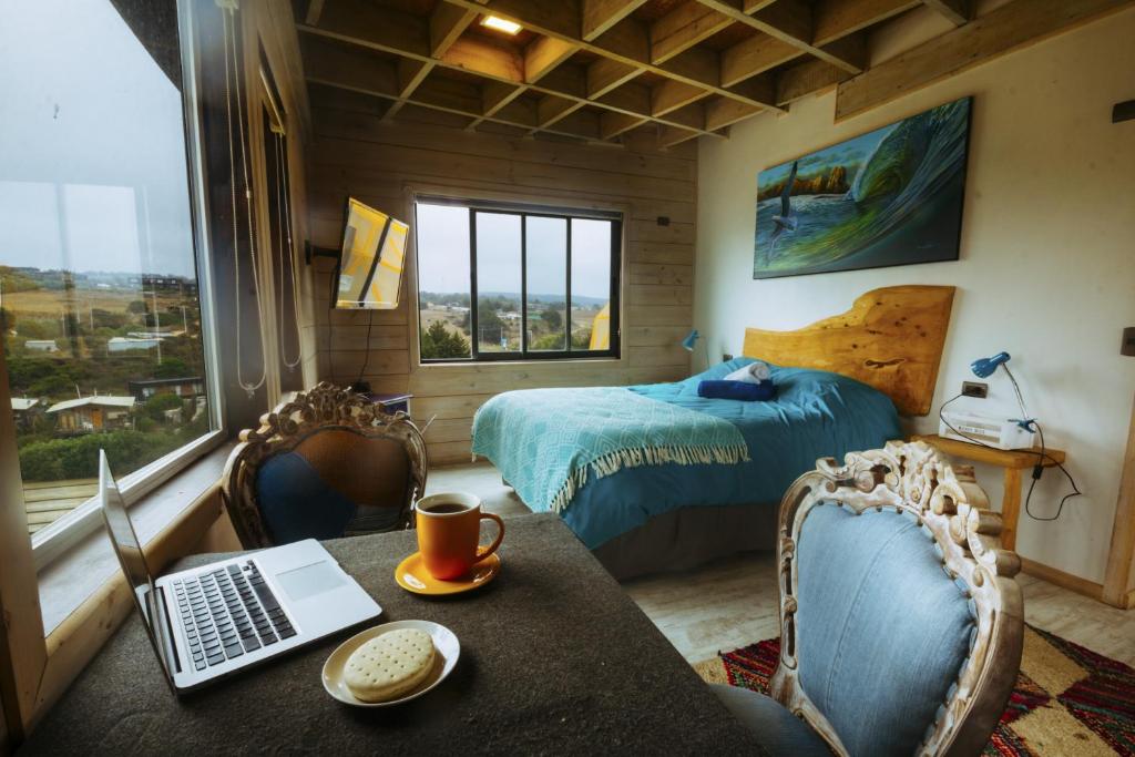 een slaapkamer met een bed en een bureau met een laptop bij The Sirena Insolente Hostel in Pichilemu