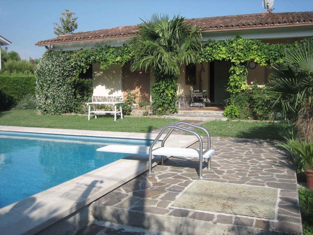 una piscina con una sedia accanto a una casa di Holiday home in Pacengo - Gardasee 21959 a Ronchi