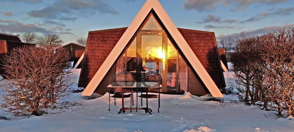 ein Glashaus im Schnee mit der Sonne im Fenster in der Unterkunft Hotelhuisje Warmenhuizen #F in Warmenhuizen