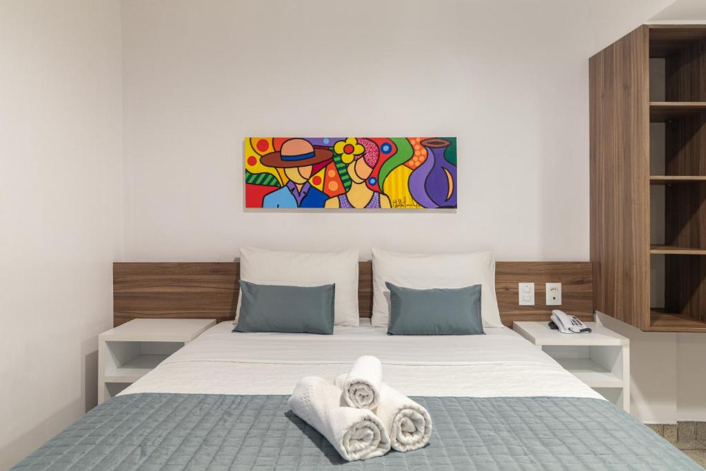 1 dormitorio con 1 cama y una pintura en la pared en Citi Hotel Express Caruaru, en Caruaru