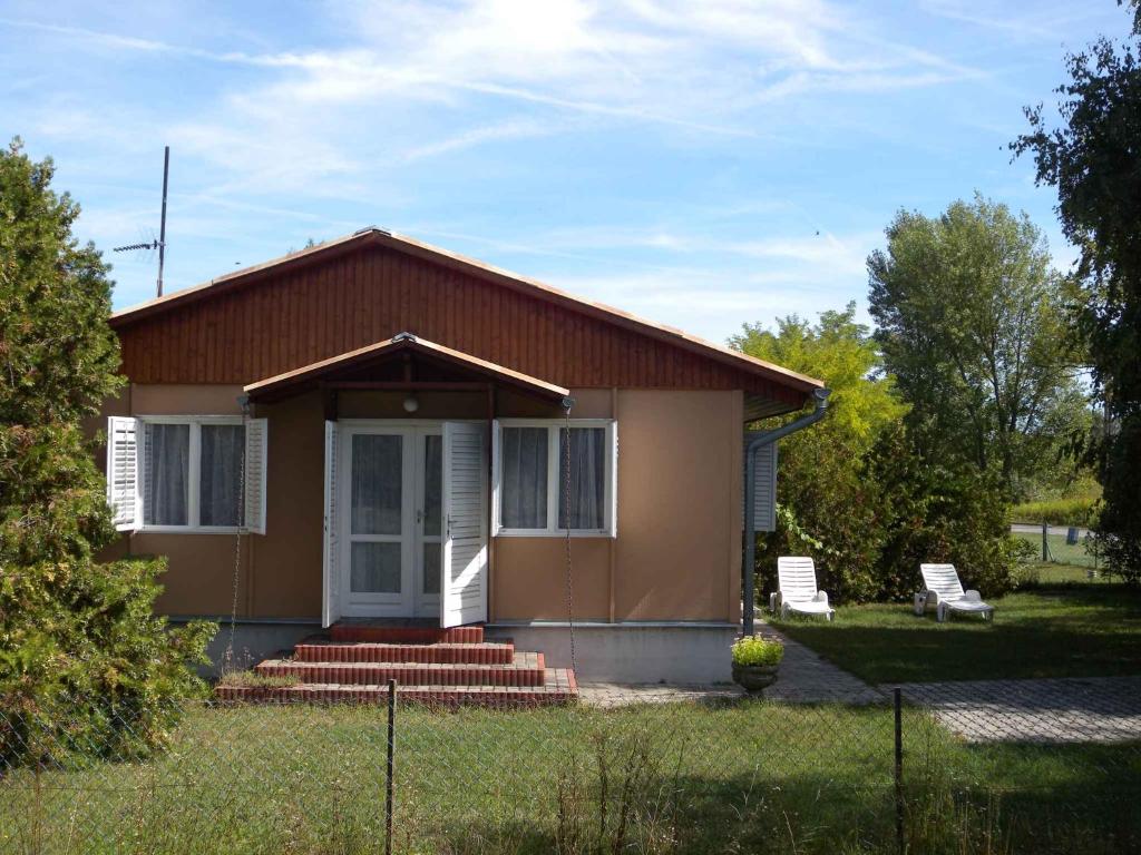 a small brown house with a porch and two chairs at Holiday home in Balatonfenyves 38374 in Balatonfenyves
