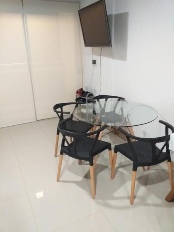 szklany stół z dwoma czarnymi krzesłami i telewizorem w obiekcie Monoambiente céntrico w mieście Posadas