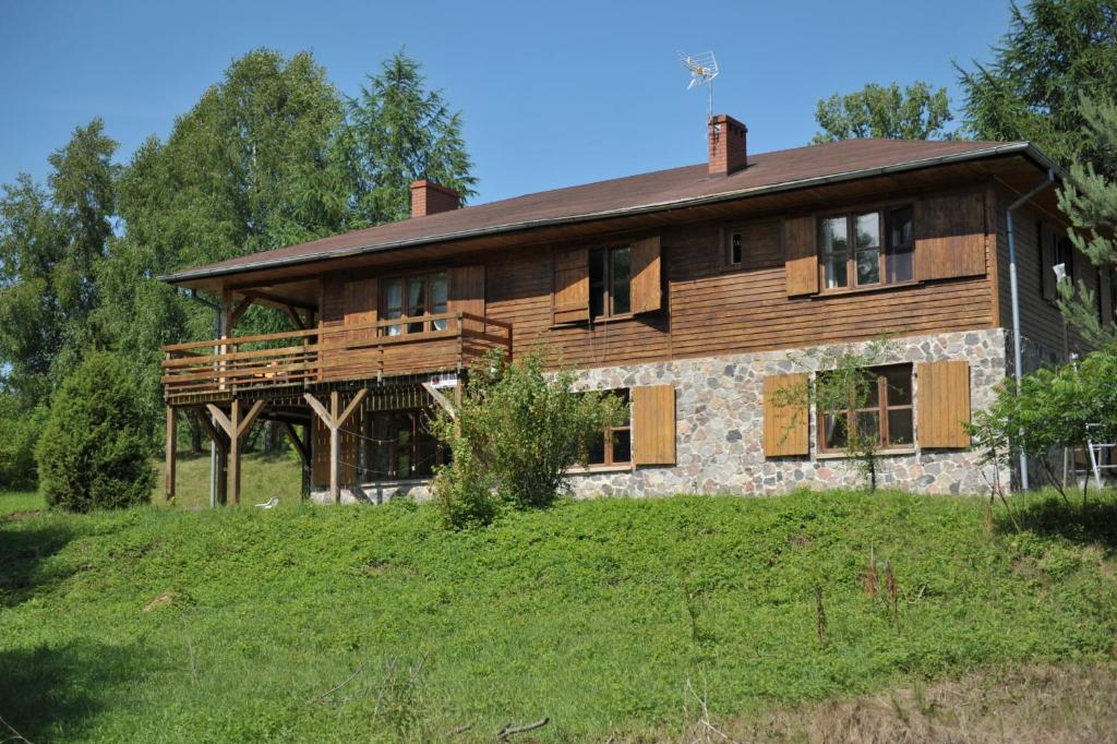 une grande maison en bois sur un champ herbeux dans l'établissement Dom nad Strugą, à Słuchowo