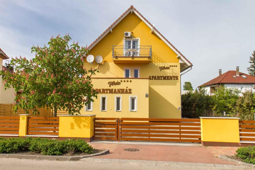 ein gelbes Haus mit einem Zaun davor in der Unterkunft Apartment in Balatonmariafürdo 19551 in Balatonmáriafürdő