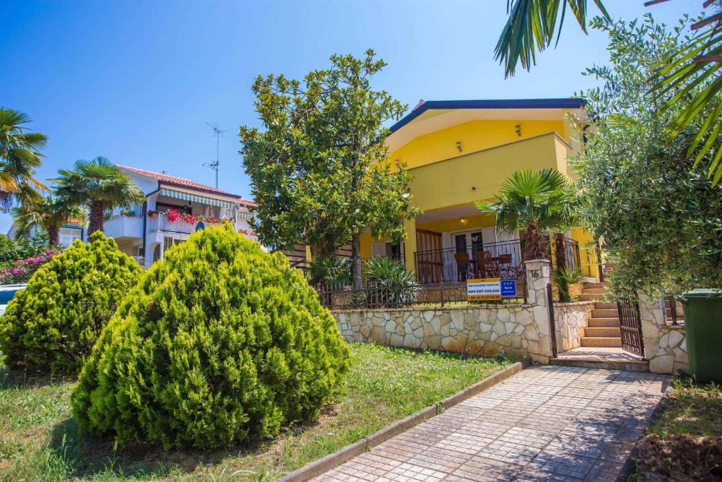 une maison jaune avec des arbres devant elle dans l'établissement Apartment in Porec/Istrien 39700, à Poreč